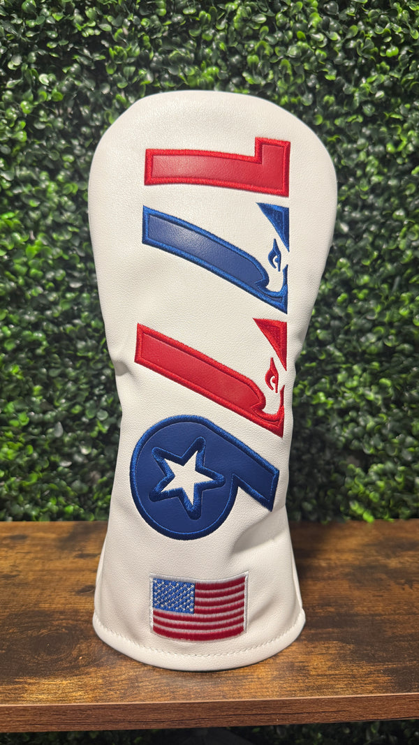 A white golf club headcover with red and blue embroidered graphics, including a stylized 'F' logo and an American flag patch near the bottom.